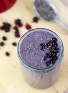 A jar and a small spoon of blueberry banana protein smoothie are on the light surface| HurryTheFoodUp