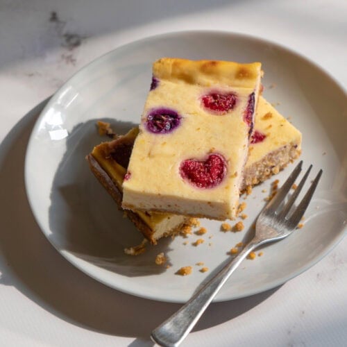 There is a white plate with two pieces of cottage cheesecake and a fork on the marble surface | Hurry The Food Up