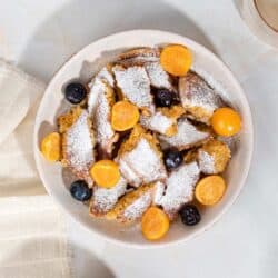 A birds eye view of a bowl of schmarrn breakfast, with fruit and yogurt, on a white marble surface | Hurry The Food Up