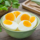 There is a green bowl with halves of boiled eggs on the wooden surface | Hurry The Food Up