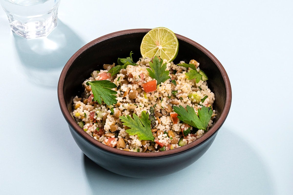 A birds eye view of a bowl of vegan lentil bolognese sprinkled with vegan cheese and basil leaves. | Hurry The Food Up