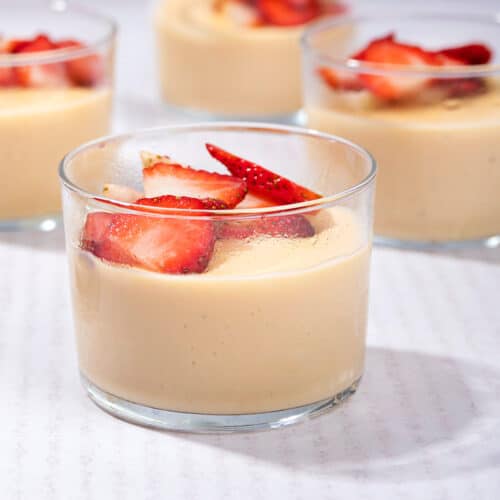 4 ramekins of custard topped with chopped strawberries on a table. | Hurry The Food Up