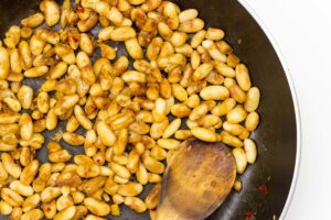 Spiced beans are being sautéed on a frying pan and stirred with a wooden spoon | Hurry The Food Up