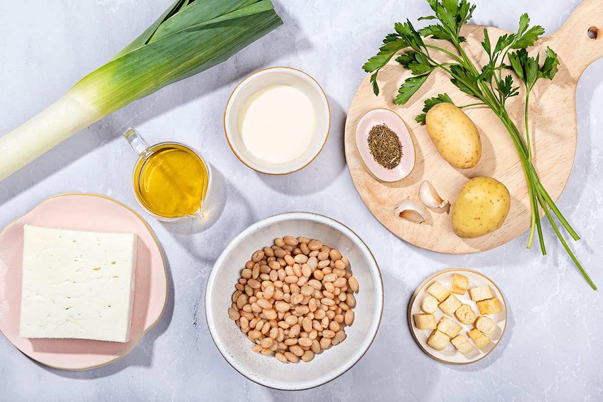 Ingredients for leek and potato soup are laid out, including leeks, potatoes, white beans, olive oil and feta cheese. | Hurry The Food Up