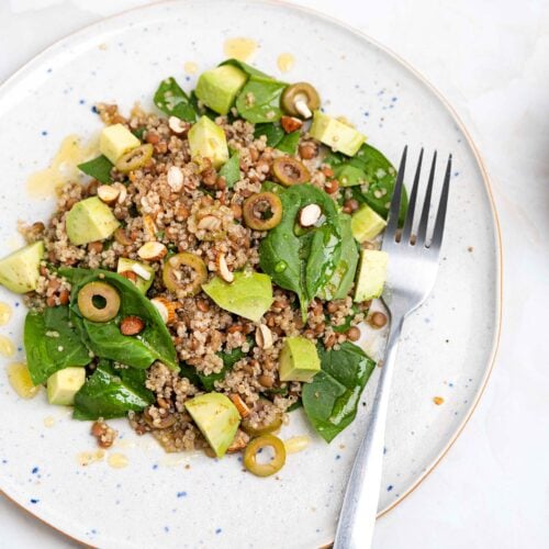 The salad is served on two plates with forks and a small bowl of olive oil and a bowl with spinach that are on the white table | Hurry The Food Up