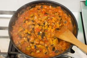 The aubergine & tomato arrabbiata sauce simmers in a frying pan, a spatula in the mix for stirring | Hurry The Food Up