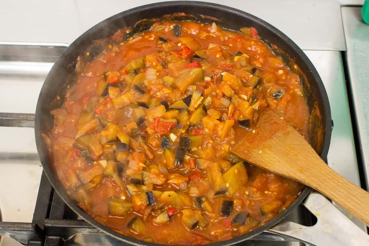 The aubergine & tomato arrabbiata sauce simmers in a frying pan, a spatula in the mix for stirring | Hurry The Food Up