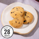 A plate of cookies sits in the middle of a table, one has a bite out of it, a time stamp is in the bottom left hand corner| Hurry The Food Up