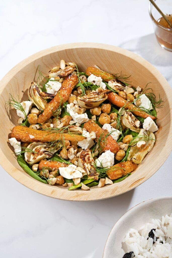 A wooden bowl of roast fennel, chickpeas, carrots with dill and feta on a white marble surface. | Hurry The Food Up