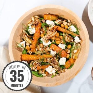 A wooden bowl of roast fennel, chickpeas, carrots with dill and feta on a white marble surface with a time stamp in the bottom left hand corner | Hurry The Food Up