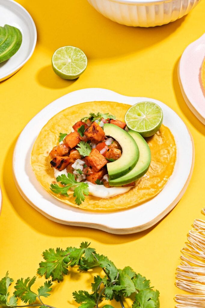 A sweet potato taco is assembled on a plate on a yellow surface | Hurry The Food Up