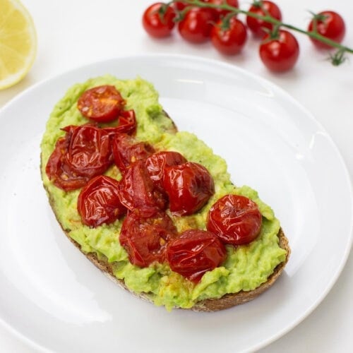 Tomato Avocado Toast is on the plate on a table with salt, lemon and cherry tomatoes #bread #olive oil | hurrythefoodup.com