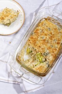 A birds eye view of the cooked vegan broccoli casserole, with portion served on a plate beside the dish | Hurry The Food Up