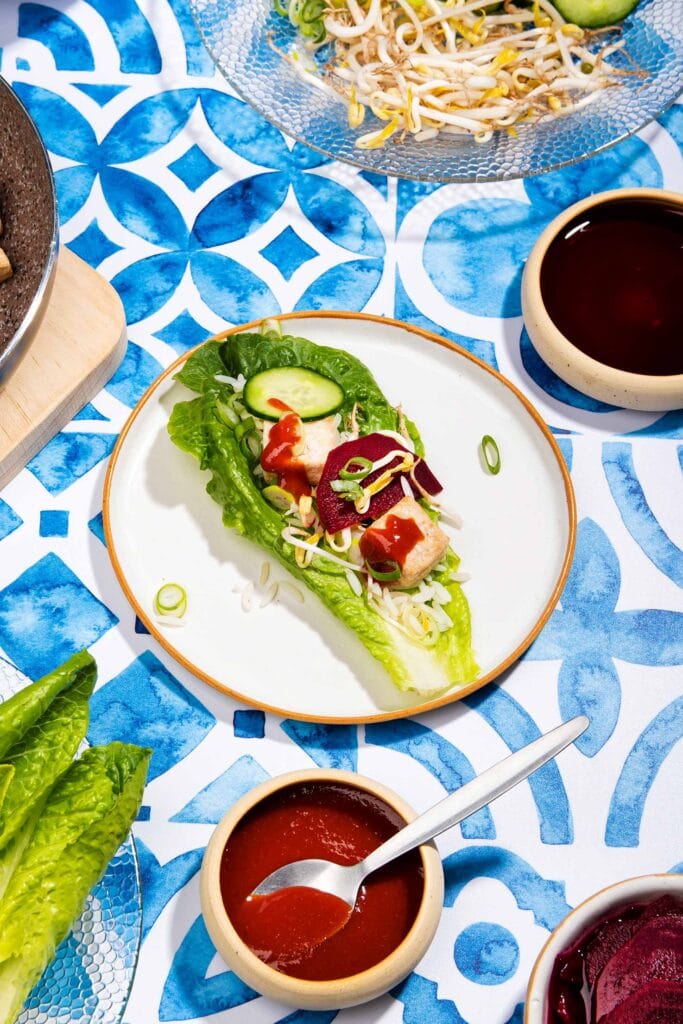 The components of a lettuce wrap are served on a table. In the centre is an assembled wrap | Hurry The Food Up