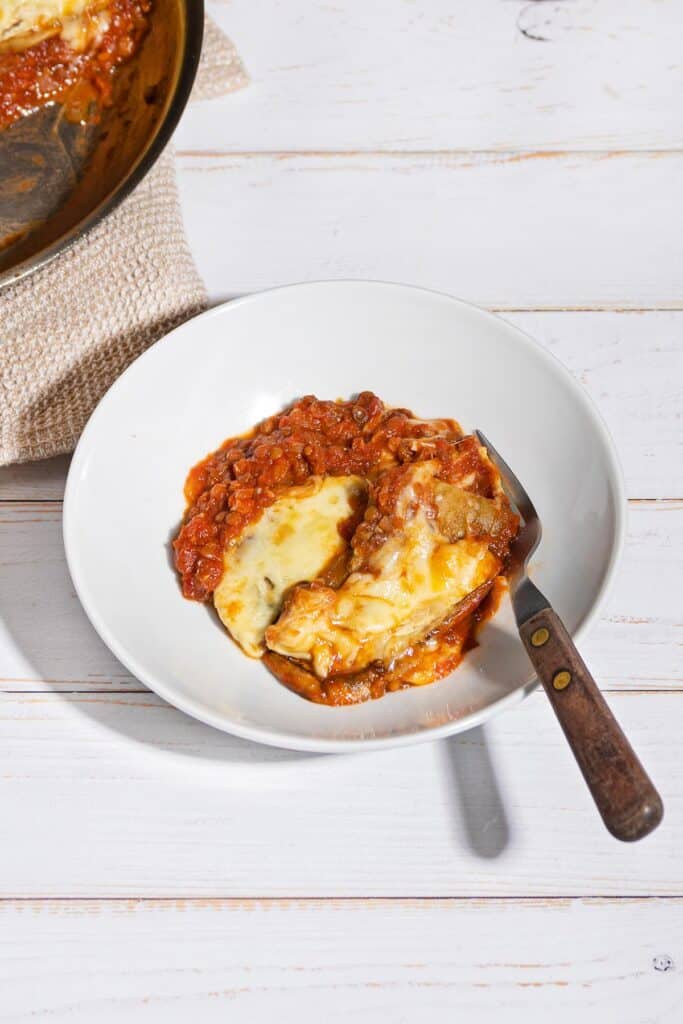 Vegetarian Moussaka is served on a plate with a pan beside it | Hurry The Food Up